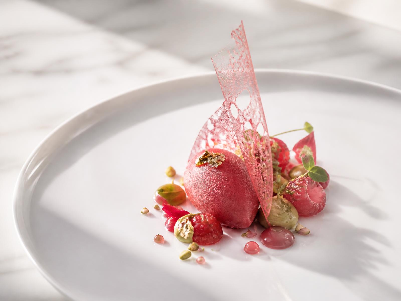 Pistachio and raspberry dessert with a sugar sail, sorbet quenelle and gold leaf